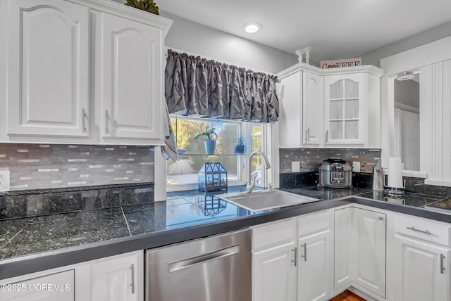 kitchen with white cabinets, decorative backsplash, stainless steel dishwasher, and sink