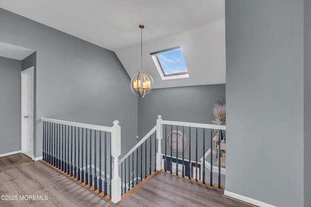 stairs featuring vaulted ceiling with skylight, a notable chandelier, and hardwood / wood-style floors