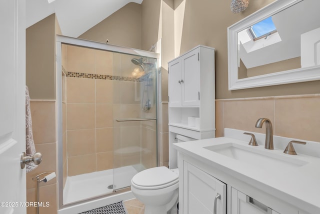 bathroom featuring vanity, toilet, a shower with door, and lofted ceiling with skylight