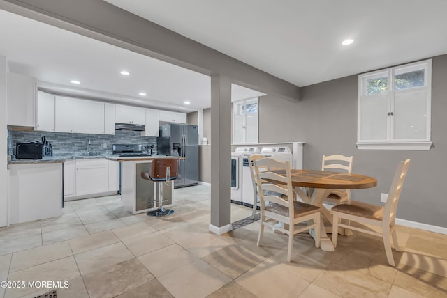 tiled dining space with independent washer and dryer and sink