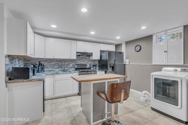 kitchen with black refrigerator with ice dispenser, gas stove, sink, white cabinets, and washer / clothes dryer