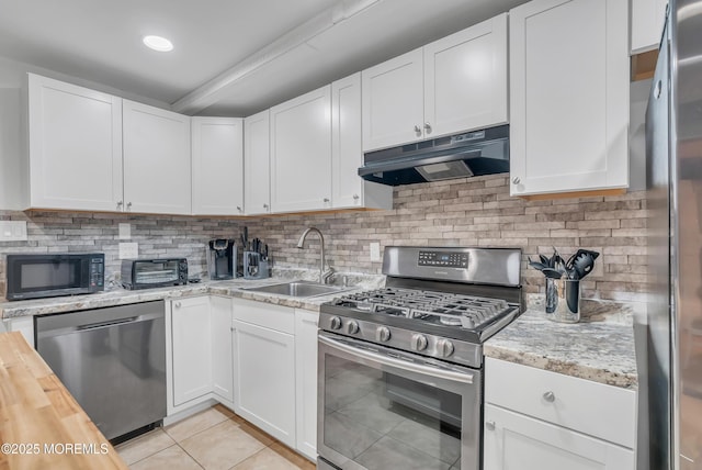 kitchen with butcher block counters, white cabinets, light tile patterned floors, and appliances with stainless steel finishes