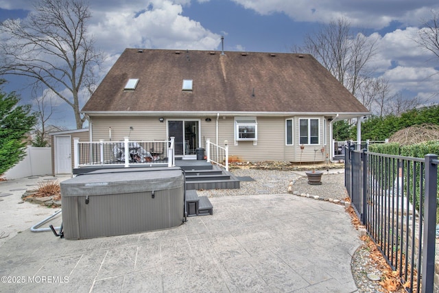 back of house featuring a deck, a hot tub, and a patio area