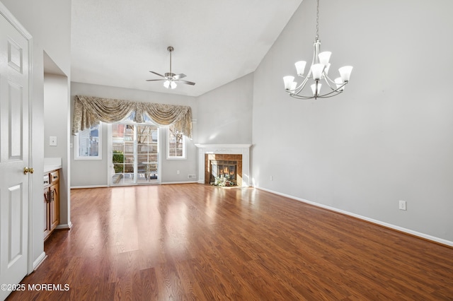 unfurnished living room with ceiling fan with notable chandelier, a fireplace, and hardwood / wood-style floors