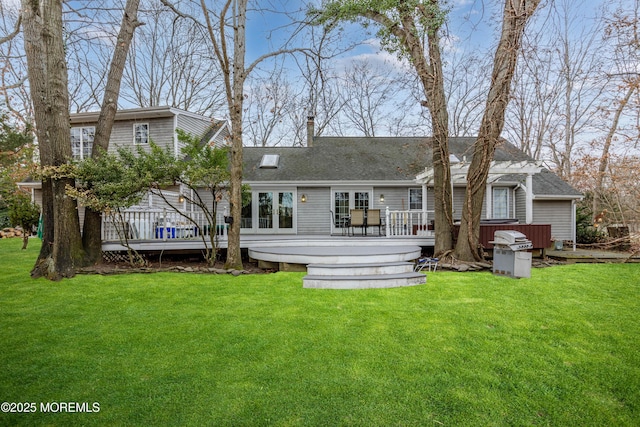 rear view of house with a deck, a lawn, and a pergola