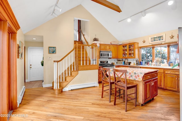 kitchen with a breakfast bar, appliances with stainless steel finishes, a baseboard radiator, and a center island