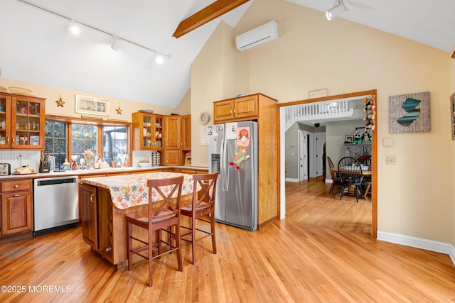 kitchen featuring an AC wall unit, a center island, stainless steel appliances, light hardwood / wood-style flooring, and a breakfast bar area