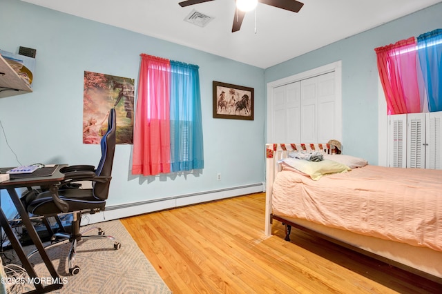 bedroom with ceiling fan, a closet, baseboard heating, and hardwood / wood-style flooring