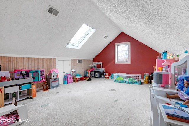 rec room featuring carpet floors, vaulted ceiling with skylight, and a textured ceiling