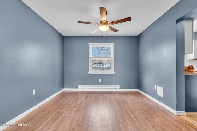 spare room featuring light wood-type flooring, ceiling fan, and baseboard heating