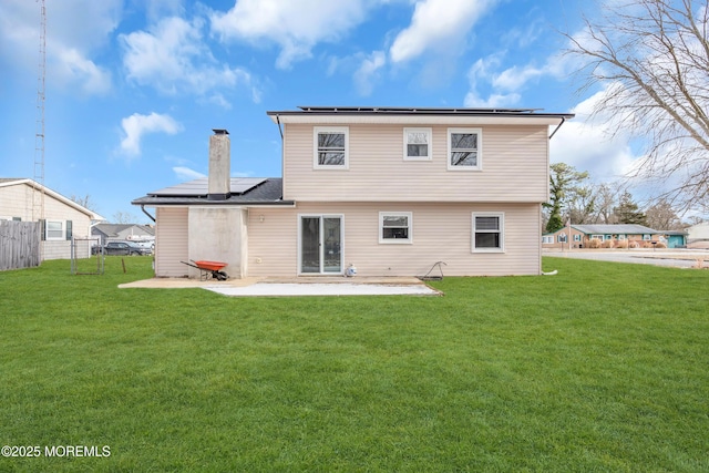 rear view of property featuring a lawn, a patio area, and solar panels