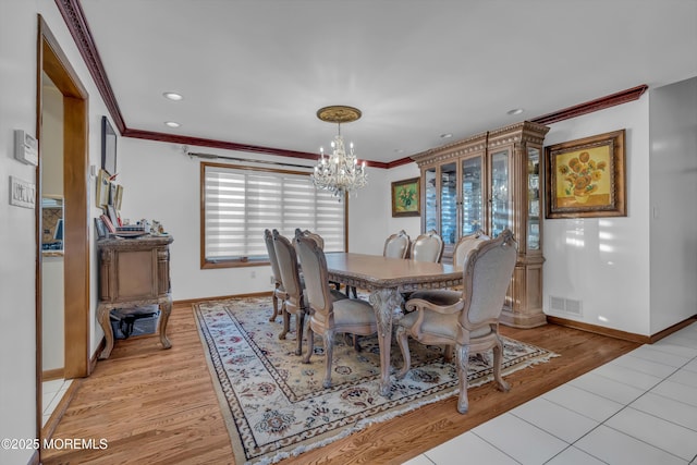 dining space featuring a notable chandelier, light hardwood / wood-style flooring, and ornamental molding