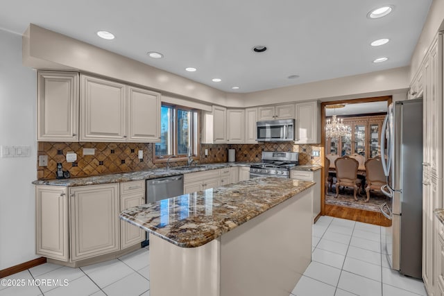 kitchen with stainless steel appliances, a center island, light tile patterned floors, stone countertops, and a notable chandelier