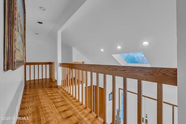 hallway featuring light hardwood / wood-style floors and lofted ceiling with skylight