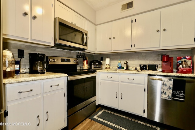 kitchen featuring sink, dark wood-type flooring, decorative backsplash, white cabinets, and appliances with stainless steel finishes