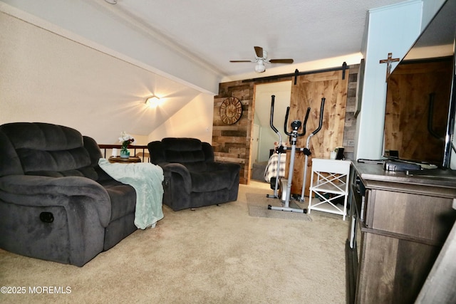 carpeted living room with vaulted ceiling with beams, a barn door, and ceiling fan