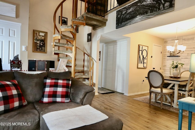 living room with a high ceiling, light hardwood / wood-style floors, a notable chandelier, and wood walls