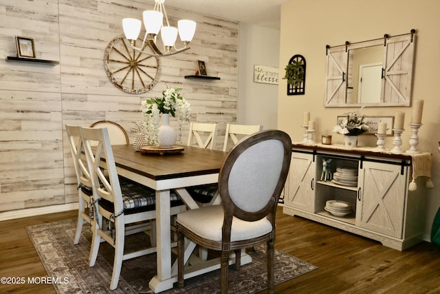 dining area featuring a barn door, dark hardwood / wood-style flooring, wooden walls, and an inviting chandelier