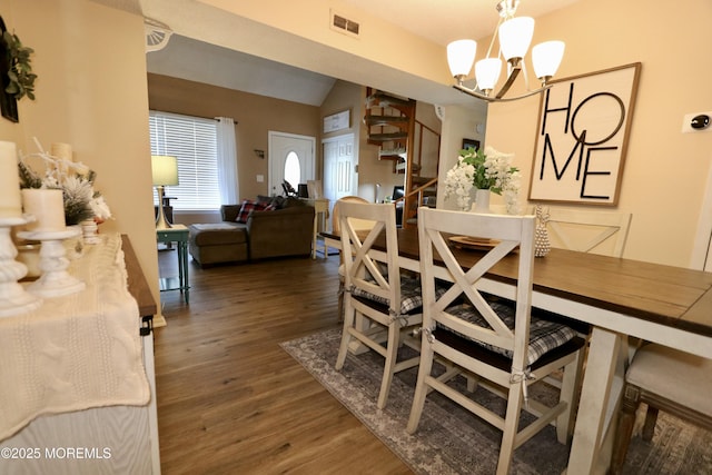 dining room with dark hardwood / wood-style floors, lofted ceiling, and a notable chandelier