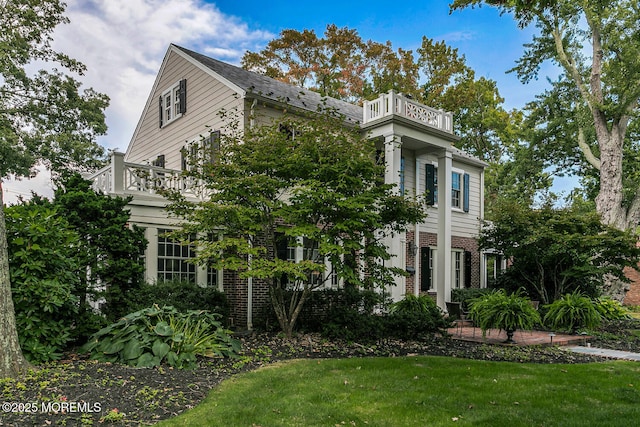 view of side of property featuring a lawn and a balcony