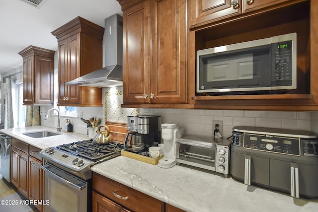 kitchen with decorative backsplash, wall chimney range hood, sink, and appliances with stainless steel finishes