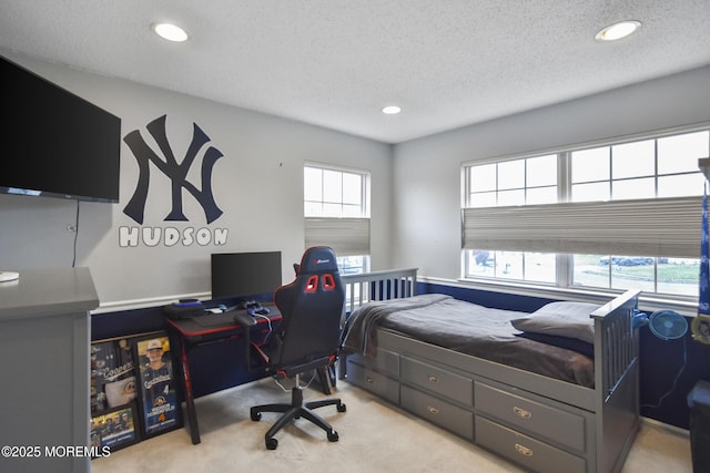 bedroom featuring multiple windows, light colored carpet, and a textured ceiling