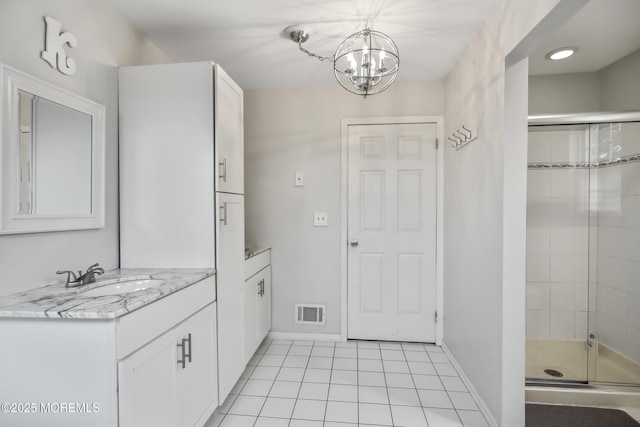 bathroom featuring tile patterned floors, vanity, a chandelier, and a shower with shower door