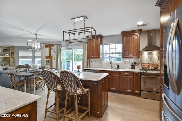 kitchen with backsplash, wall chimney exhaust hood, stainless steel appliances, pendant lighting, and a center island