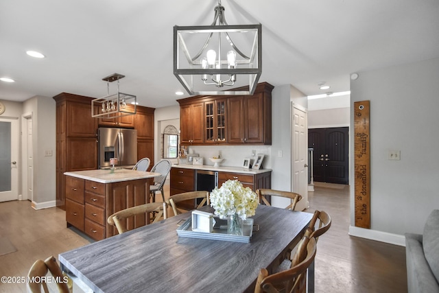 dining space with wood-type flooring, beverage cooler, and a chandelier