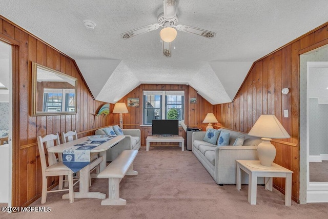 living room featuring ceiling fan, light colored carpet, lofted ceiling, and a textured ceiling