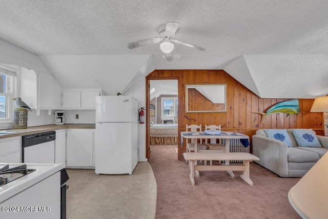 kitchen with lofted ceiling, white appliances, white cabinetry, and wooden walls