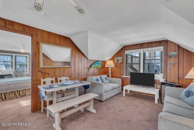 carpeted living room with a textured ceiling, vaulted ceiling, a wealth of natural light, and ceiling fan