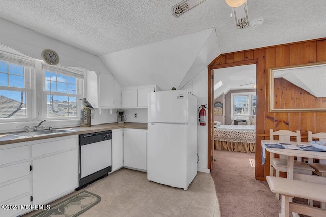 kitchen featuring white appliances, a healthy amount of sunlight, sink, white cabinetry, and wood walls