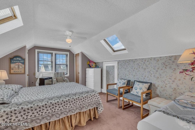 bedroom featuring a textured ceiling, ceiling fan, lofted ceiling with skylight, and carpet floors