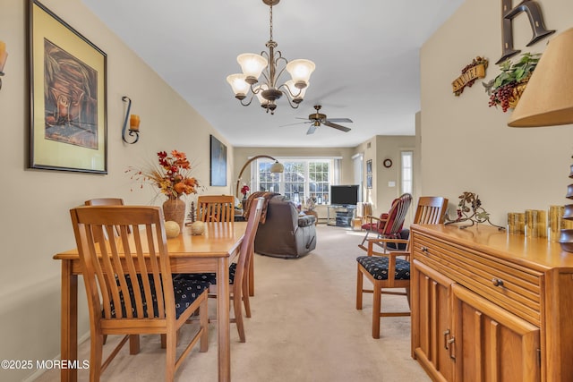 dining space featuring light colored carpet and ceiling fan with notable chandelier