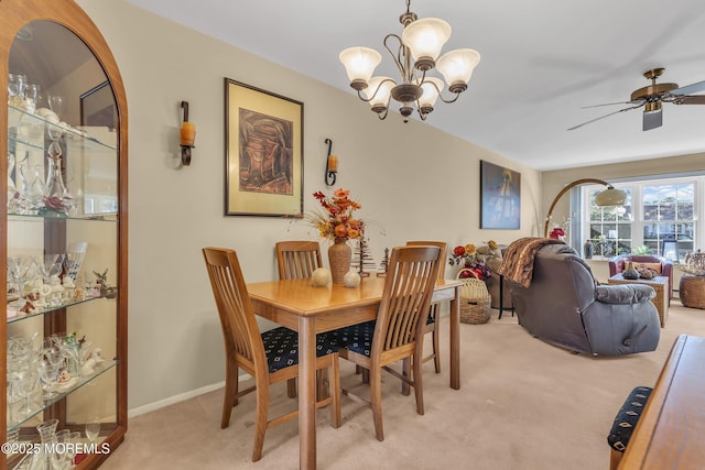 carpeted dining area featuring ceiling fan with notable chandelier