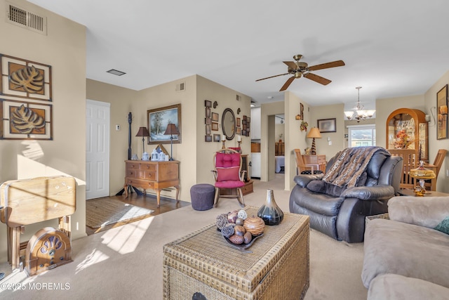 carpeted living room featuring ceiling fan with notable chandelier