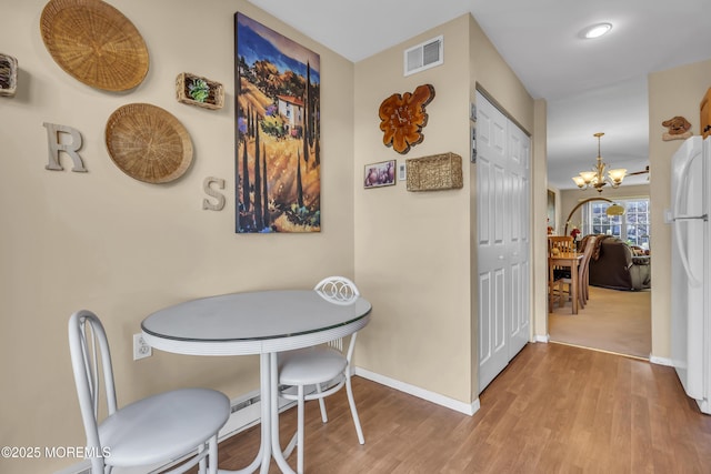 dining area featuring hardwood / wood-style floors and an inviting chandelier