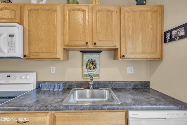 kitchen with light brown cabinetry, sink, and white appliances