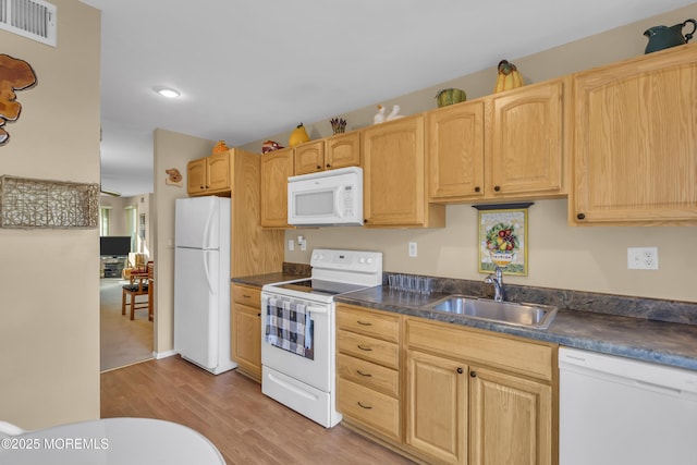 kitchen featuring light brown cabinetry, sink, white appliances, and light wood-type flooring