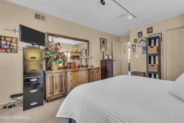 bedroom with light colored carpet and track lighting