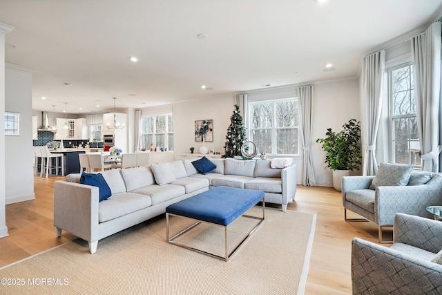 living room featuring ornamental molding, a wealth of natural light, and light hardwood / wood-style floors