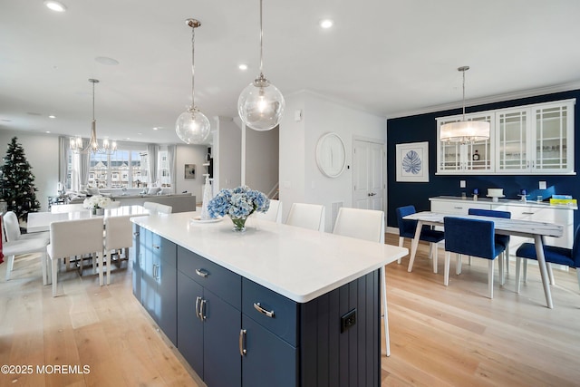 kitchen featuring blue cabinets, white cabinetry, a center island, and light hardwood / wood-style floors