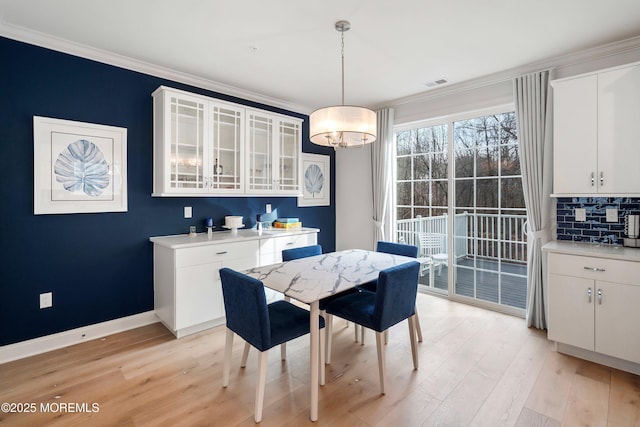 dining room with ornamental molding and light wood-type flooring