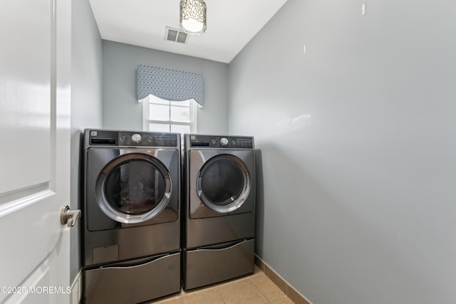 laundry area featuring light tile patterned floors, visible vents, washing machine and dryer, laundry area, and baseboards