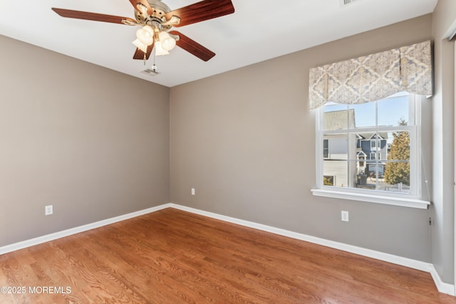 empty room featuring ceiling fan, baseboards, and wood finished floors