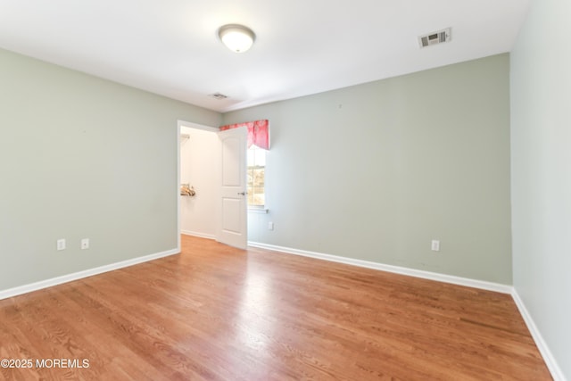 unfurnished room featuring baseboards, visible vents, and light wood-style flooring