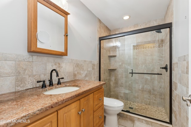 bathroom with a shower stall, toilet, and vanity