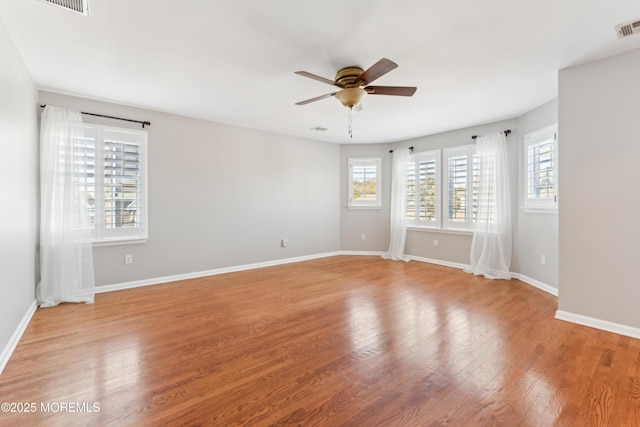 empty room featuring baseboards, a ceiling fan, a wealth of natural light, and light wood-style floors