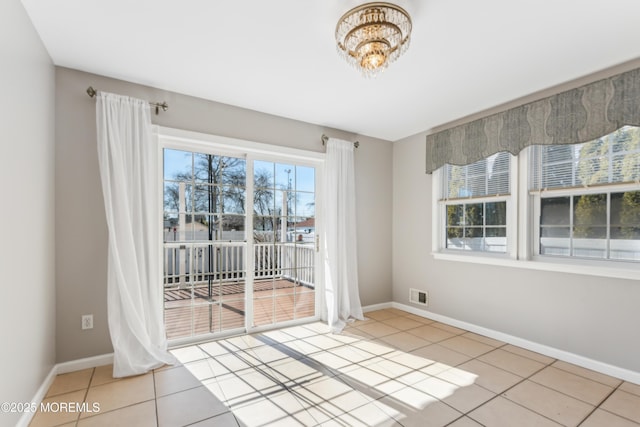 tiled spare room with visible vents, baseboards, and an inviting chandelier